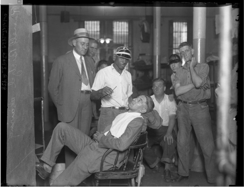 Convicted murderer, Russell Beitzel getting a shave in prison as other inmates look on, Los Angeles, Calif., 1928. [Photo courtesy of UCLA Digital Collection]